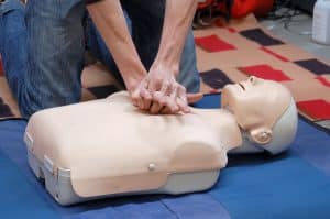 Two hands applying CPR techniques to a training dummy
